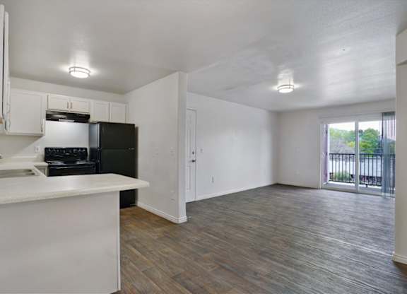 A kitchen with white cabinets and a black fridge.