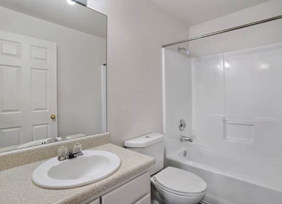 A white bathroom with a sink, toilet, and bathtub.