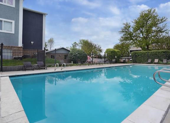 A blue swimming pool surrounded by a black fence.