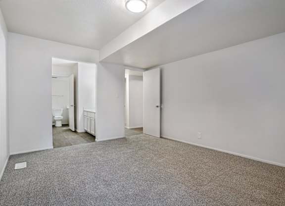 A spacious room with a carpeted floor and white walls.