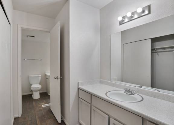 A white bathroom with a toilet, sink, and mirror.