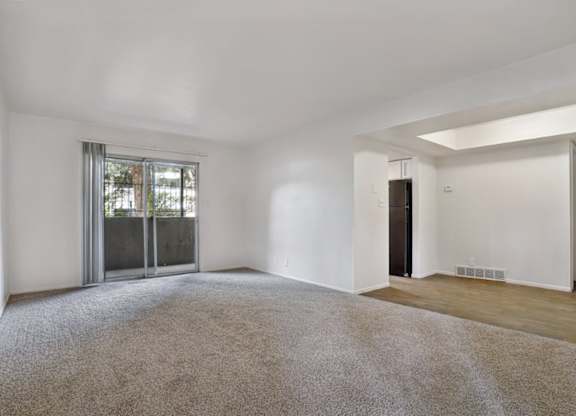 A spacious room with a carpeted floor and a sliding glass door.