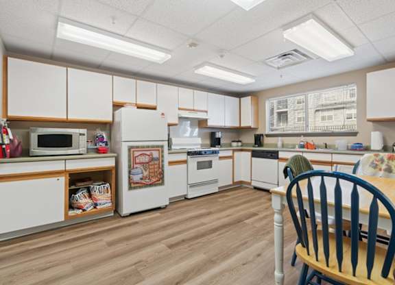 A kitchen with white cabinets and wooden floors.