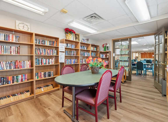 A library with a table and chairs in the middle of the room.