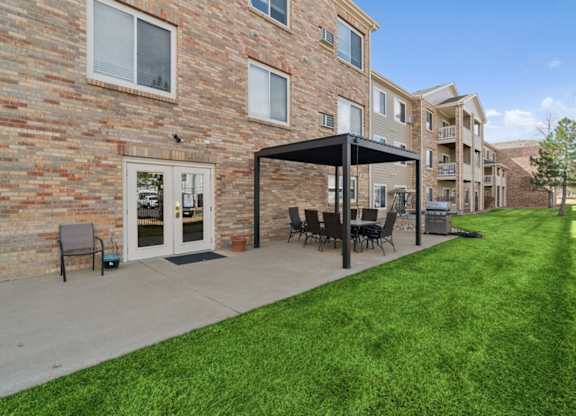 A patio with a table and chairs is in front of a brick building.