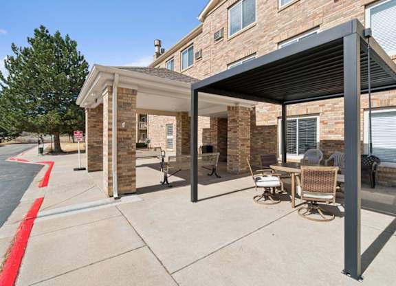 A patio with a table and chairs is covered by a black awning.