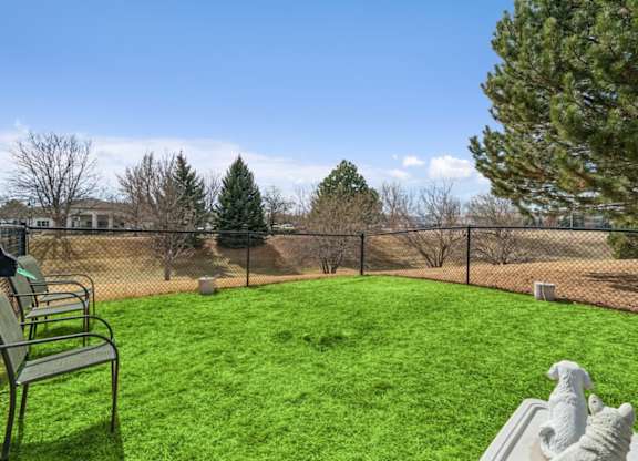 A backyard with a green lawn and a bench.