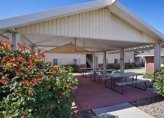A covered patio area with tables and benches.
