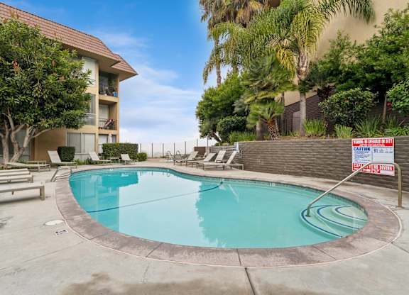 A pool surrounded by a concrete patio and a fence.