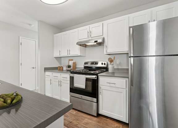 A modern kitchen with white cabinets and stainless steel appliances.
