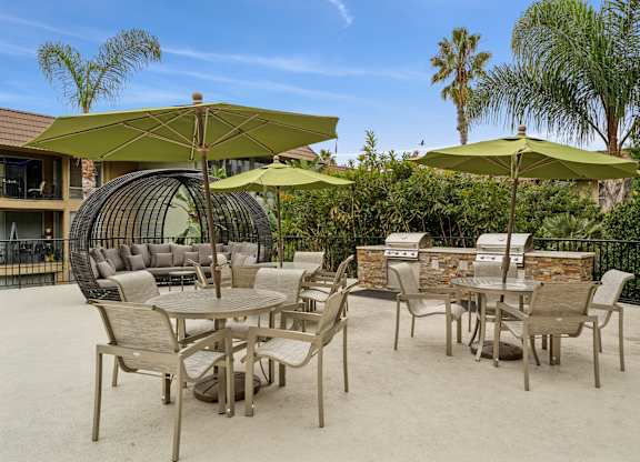A patio with chairs and tables under umbrellas.