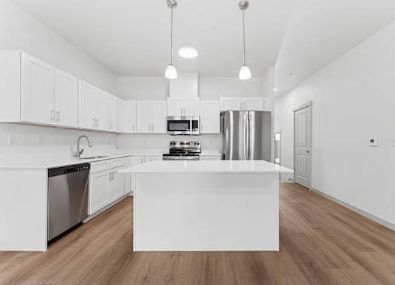 A modern kitchen with a white island and stainless steel appliances.