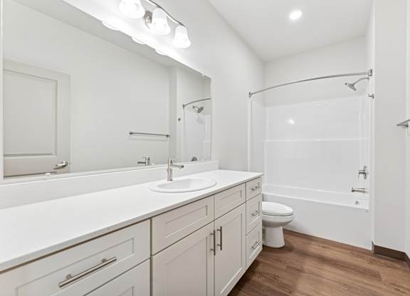 A white bathroom with a toilet, sink, and shower.