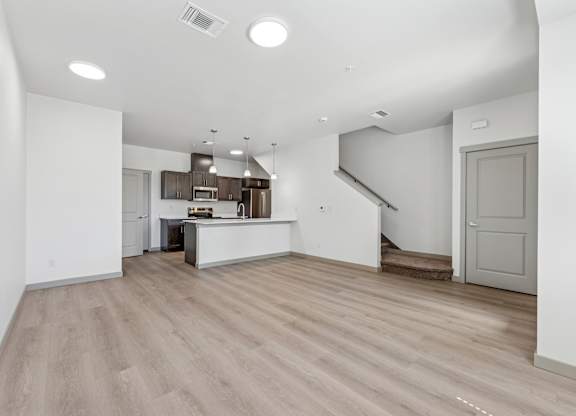 A spacious kitchen with a bar area and a staircase in the background.