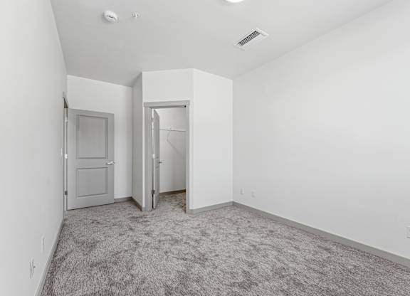 A room with a carpeted floor and two doors.