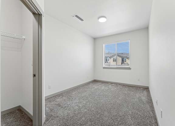 A room with a carpeted floor and a window showing a building outside.
