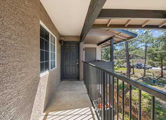 A balcony with a black door and a metal railing.