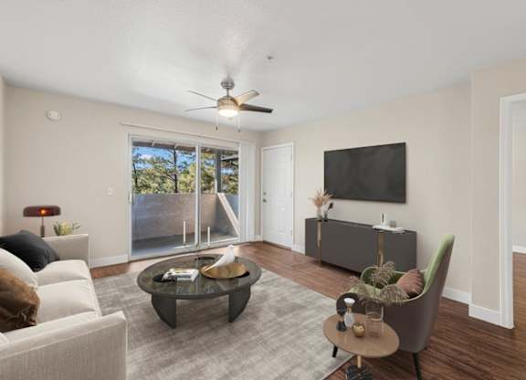 A living room with a white couch, a coffee table, a chair, and a flat screen TV mounted on the wall.