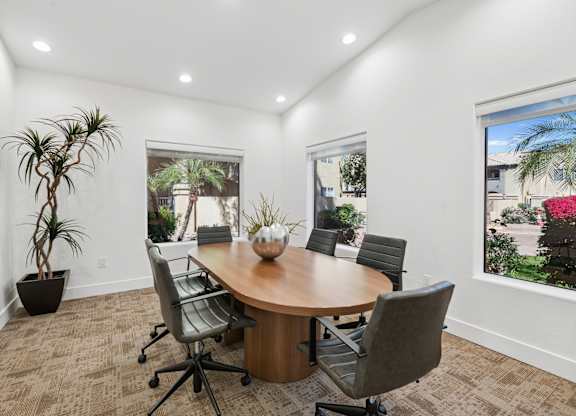 A conference room with a large table surrounded by chairs.