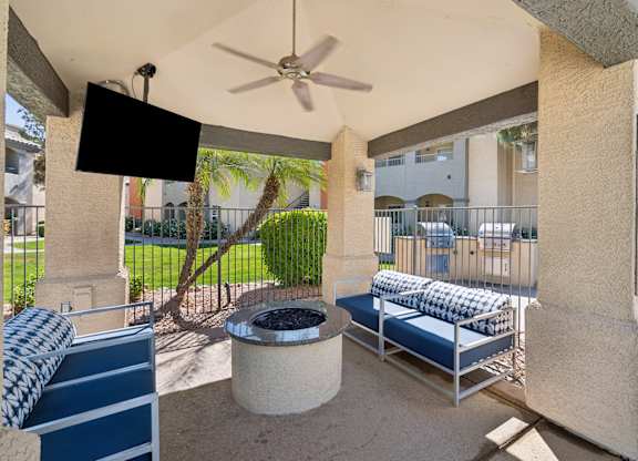 A patio with a couch, a table, and a fan.