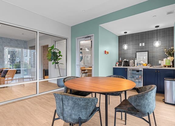 a dining area with a table and chairs and a kitchen in the background