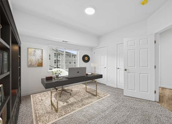 A room with a laptop on a desk and a clock on the wall.