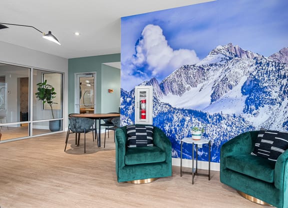 a room with two green chairs and a large mural of a snowy mountain on the wall