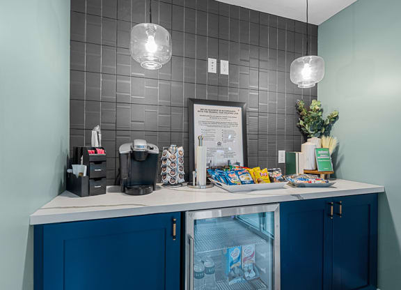 a coffee bar with blue cabinets and a white counter top with a coffeemaker and coffee