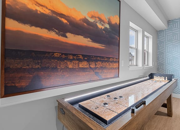 a game room with a large screen tv and a shuffleboard table