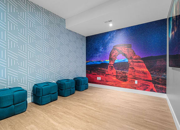 a room with two blue chairs and a large painting on the wall