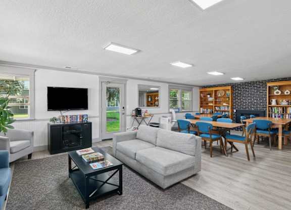 A living room with a grey couch, a black coffee table, and a television.