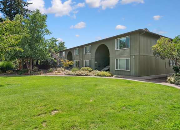 A green lawn in front of a grey building.