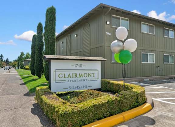 A sign for Clairmont Apartments is in front of a building.