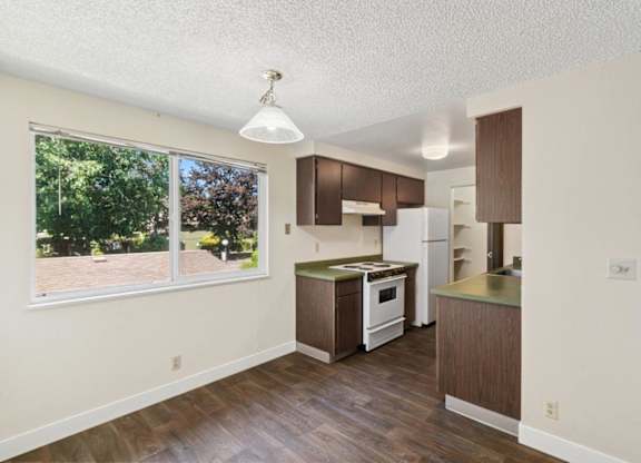 A kitchen with white appliances and brown cabinets.