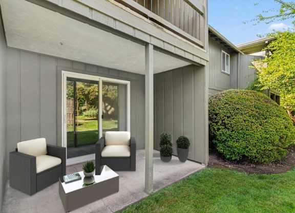 A grey house with a white chair and table outside.