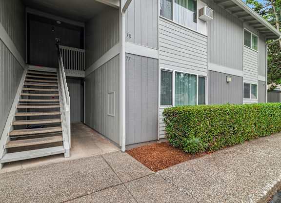 A grey building with a staircase leading to a door.