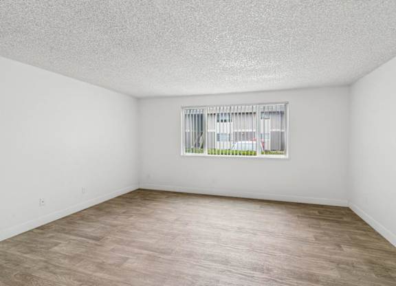 A room with a window and wooden flooring.
