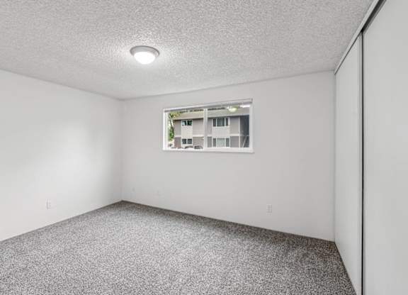 A room with a window and carpeted floor.