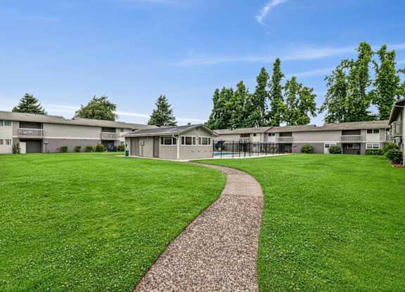 A grassy area with a concrete walkway leading to a building.
