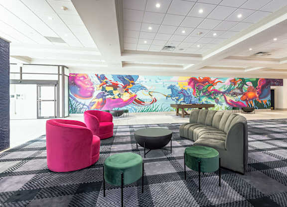A room with a mural on the wall and a variety of seating options.