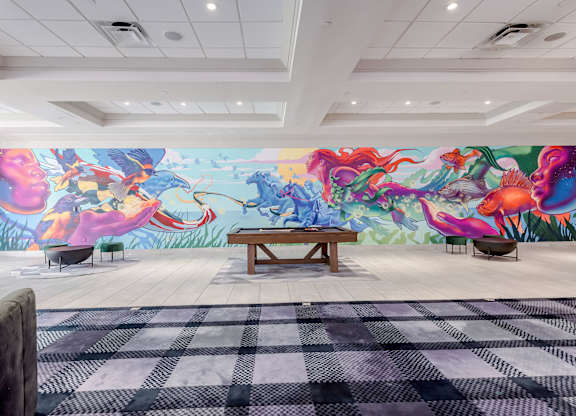 A room with a large mural of colorful sea creatures and a bench in the center.