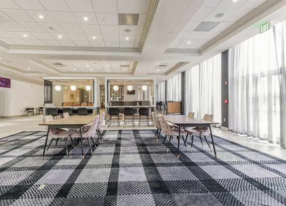 A room with a checkered carpet and a long table with chairs.