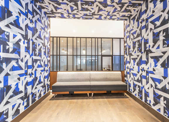 A room with a blue and white patterned wallpaper and a grey bench.