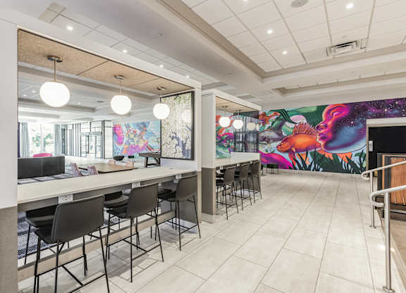 A white table with chairs is in front of a colorful mural.
