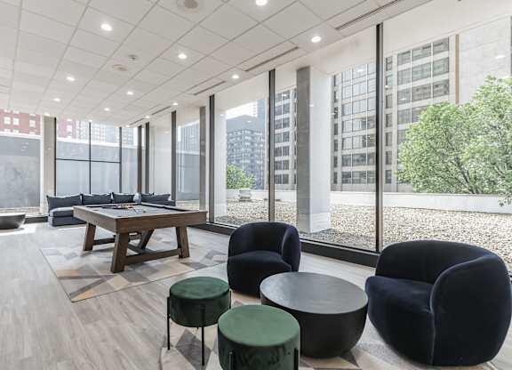 A modern living room with a long table and black chairs.