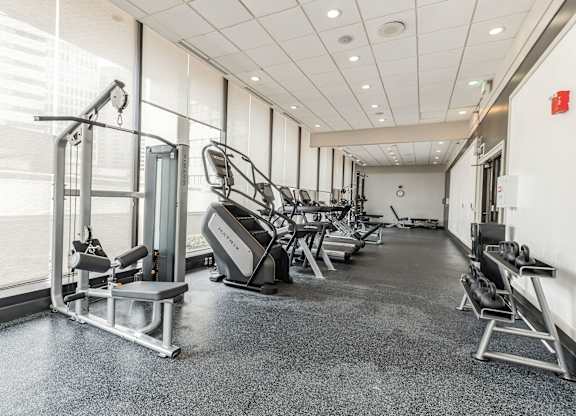 A gym with a variety of equipment including treadmills, weights, and exercise machines.