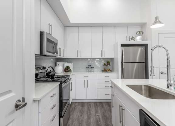 A modern kitchen with white cabinets and stainless steel appliances.