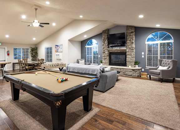 A pool table is in the middle of a room with a fireplace and a couch.