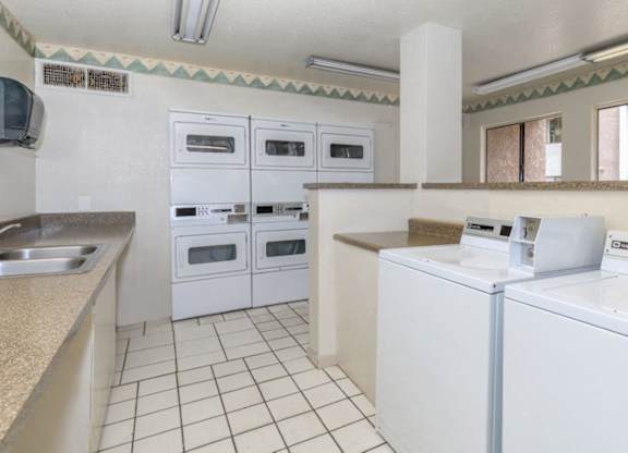 A kitchen with white appliances and a tile floor.