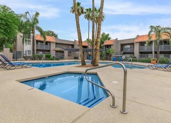 A swimming pool surrounded by palm trees and lounge chairs.
